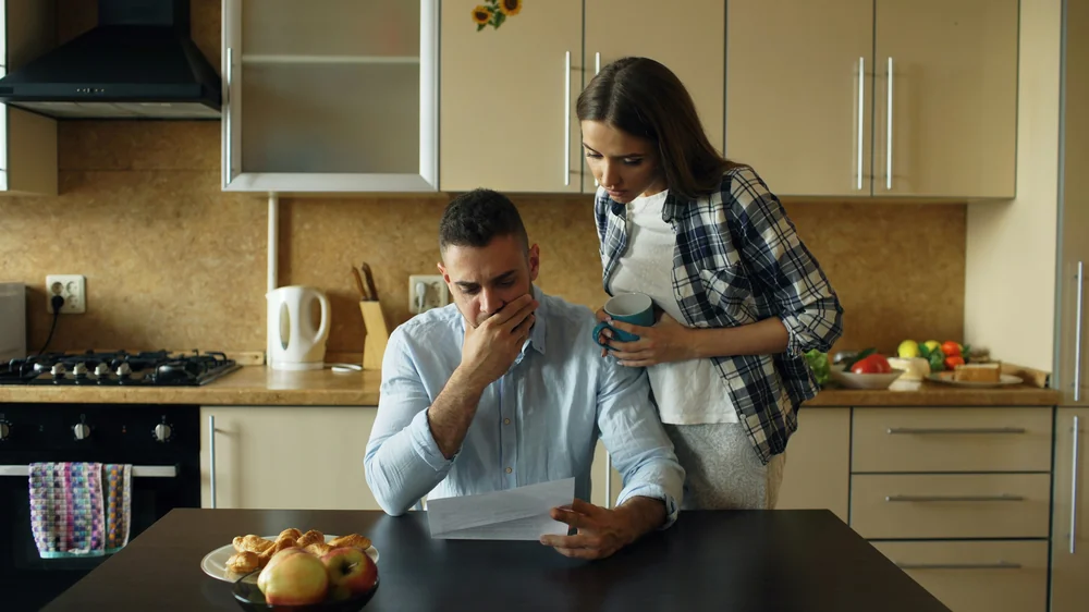 Pareja preocupada mirando una factura en la cocina